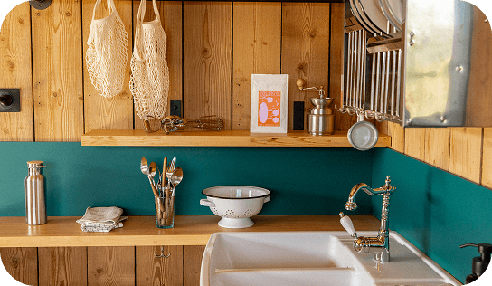 IMAGE-FAMILLE-2 Cuisine rustique avec murs en bois, étagères ouvertes, évier blanc et robinet vintage.