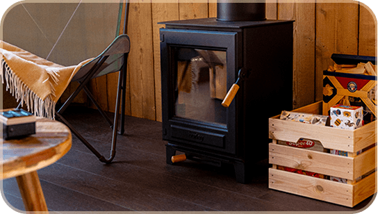 IMAGE-FAMILLE Poêle à bois dans un intérieur de chalet confortable, caisse avec des jeux, chaise avec couverture.