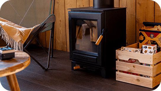 IMAGE-FAMILLE Poêle à bois dans une cabane confortable avec caisse à bois et chaise.
